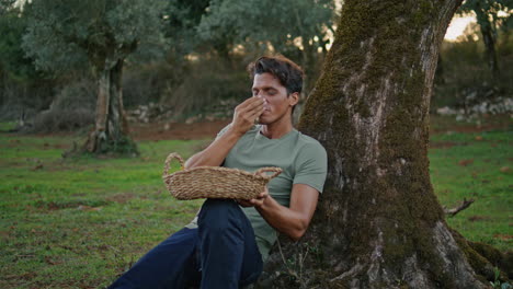 Positive-man-smelling-olives-tree-landscape-close-up.-Happy-farmer-having-break