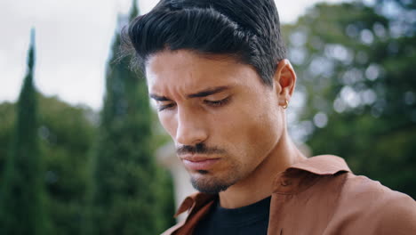 Latin-guy-looking-down-park-vertical-closeup.-Serious-businessman-standing-alone