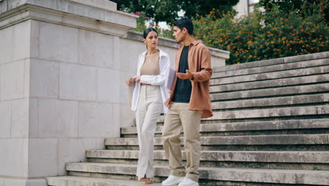 Business-couple-walking-stairs-at-work-break-vertical.-Colleagues-talking-on-way