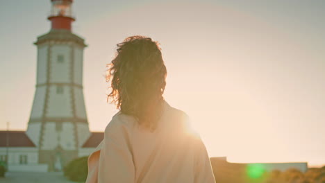 Attractive-girl-spinning-sun-at-lighthouse.-Carefree-woman-walk-evening-seaside