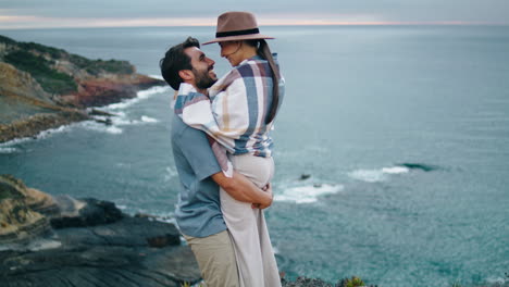 Loving-couple-hugging-coast-hill.-Happy-man-spinning-woman-near-calm-ocean-view