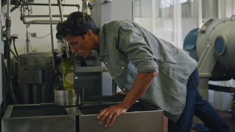 Involved-worker-smelling-oil-at-fabric-container-closeup.-Man-preparing-product