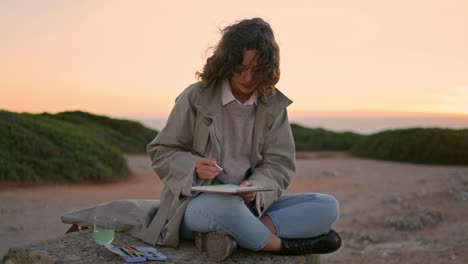 Creative-girl-drawing-sketch-at-evening-ocean-vertically.-Focused-woman-painting