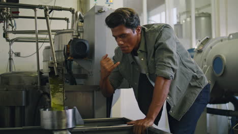 Professional-guy-tasting-olive-oil-at-factory-close-up.-Man-controlling-process