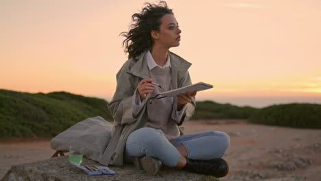 Young-woman-painting-sunset-vertically-Focused-talented-student-admiring-nature