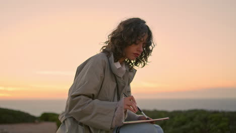 Serene-woman-drawing-picture-at-evening-ocean-vertical.-Inspired-artist-enjoying