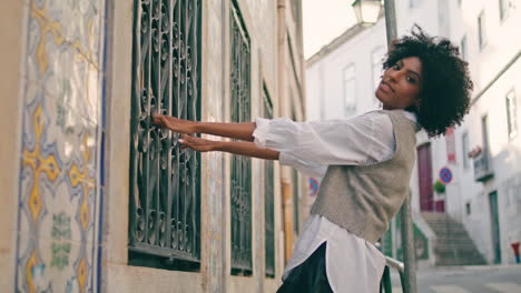 Modelo-De-Moda-Posando-Calle-Sosteniendo-Barras-En-La-Ventana-Del-Edificio-Antiguo.-Chica-Disfruta-Caminando