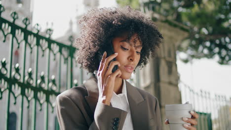 Mujer-De-Pelo-Negro-Llamando-A-Móvil-Sosteniendo-Café-Al-Aire-Libre-De-Cerca.-Señora-Hablando