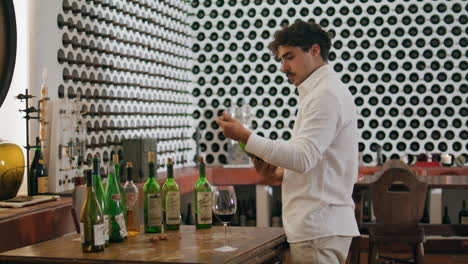 Sommelier-uncorking-wine-bottle-preparing-degustation-in-winery-cellar-vertical