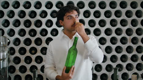 Winemaker-opening-wine-bottle-sniffing-cork-in-winery-cellar-vertical-closeup