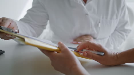 Woman-hands-showing-documents-details-to-cosmetologist-close-up.-Paper-agreement