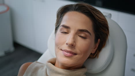 Cosmetology-client-looking-camera-lying-on-medical-chair-modern-clinic-close-up.