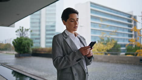 Thoughtful-manager-typing-mobile-phone-on-go.-Focused-business-owner-text-cell
