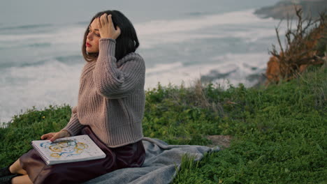 Dreamy-woman-relaxing-blanket-with-book-looking-evening-ocean.-Model-posing.