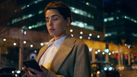 Mujer-Desplazándose-Por-La-Calle-Nocturna-Del-Teléfono-Inteligente.-Exitosa-Empresaria-Tardía-Espera-Taxi