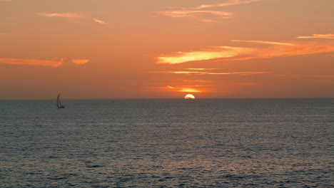 Ruhiger-Blick-Auf-Den-Sonnenuntergang-Am-Meer-Im-Sommer.-Einsames-Jachtboot,-Das-In-Ruhigem-Wasser-Segelt