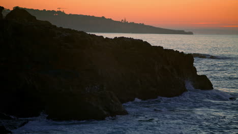 Mountain-hill-silhouette-at-sunset-sea-beach.-Dark-cliff-at-calm-ocean-evening