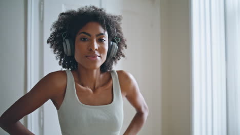 Yoga-Frau-Lächelt-Mit-Der-Kamera-Nach-Hause.-Afrikanische-Sportlerin-Mit-Kopfhörern-Streckt-Sich-Allein