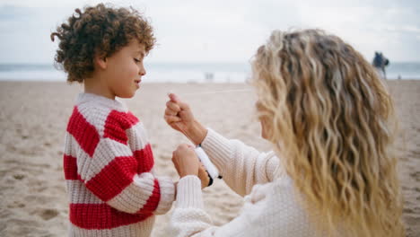 Madre-Ayudando-A-Volar-Cometas-En-El-Primer-Plano-De-La-Playa.-Hijo-Adorable-Sonriente-Sosteniendo-Hilo