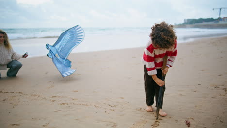 Cute-kid-drawing-sand-on-autumn-seaside.-Happy-family-play-having-fun-together