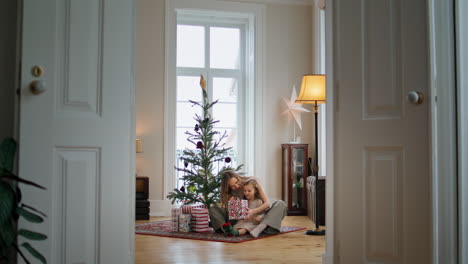 Entzückende-Familie,-Die-Geschenke-In-Der-Nähe-Des-Weihnachtsbaums-Auspackt.-Zarte-Frau-Umarmt-Kind