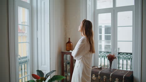 Mujer-Pensativa-Mirando-La-Ventana-Al-Interior-Luminoso.-Señora-Estirando-Las-Manos-Descansando