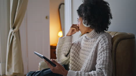 Serene-woman-using-tab-at-evening-apartment-closeup.-African-lady-closed-eyes