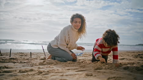 Junge-Mutter-Spielt-Mit-Süßem-Jungen-Am-Strand.-Glückliche-Familie-Baut-Gemeinsam-Sandburgen.