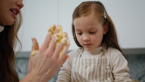 Mother-daughter-hands-rolling-dough-at-home-close-up.-Woman-teaching-kid-baking