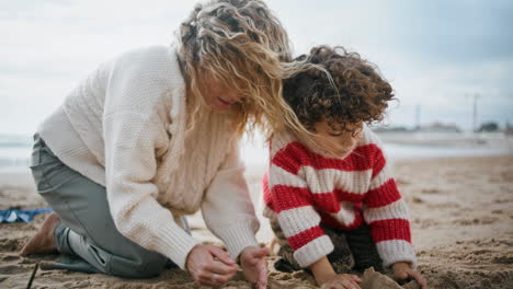 Familie-Baut-Sandburgen-Am-Kühlen-Strand.-Alleinerziehende-Mutter-Spielt-Mit-Ihrem-Kleinen-Lockigen-Sohn