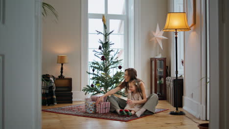 Familia-Feliz-Desempacando-Regalos-En-Una-Casa-Acogedora.-Mamá-Hija-Pasando-Navidad