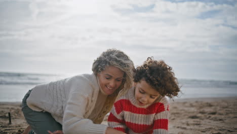 Closeup-mother-playing-son-on-ocean-weekend.-Happy-family-building-sand-castle