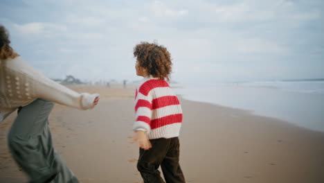 Happy-boy-running-ocean-shore-barefoot.-Cheerful-son-playing-airplane-pilot-game