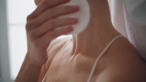 Woman-hand-rubbing-neck-with-lotion-home-close-up.-Unknown-girl-using-cotton-pad