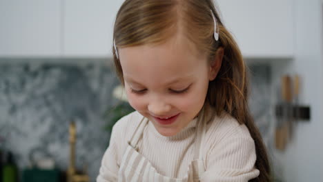 Funny-child-rolling-sleeves-up-at-kitchen-portrait.-Cute-baby-baking-at-home