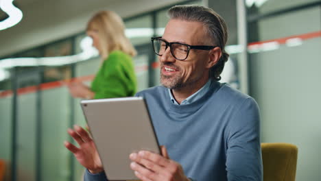 Smiling-man-greeting-video-chat-in-office-closeup.-Happy-director-waving-hand