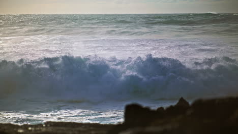 Ocean-surf-crashing-coast-on-sunny-day.-Extreme-stormy-waves-splashing-rocky