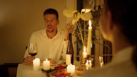 Positive-man-speaking-at-candles-room-closeup.-Newlyweds-having-romantic-date