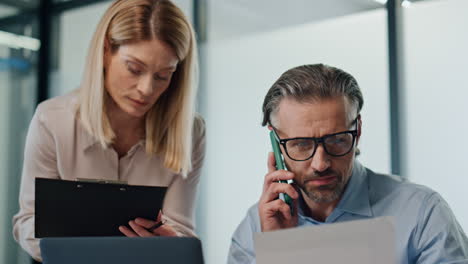 Serious-colleagues-working-at-office-closeup.-Busy-director-calling-smartphone