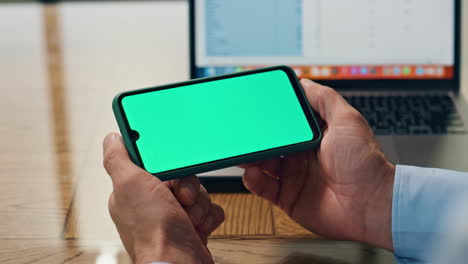 Boss-fingers-hold-mockup-cellphone-at-office-closeup.-Man-watching-chroma-phone