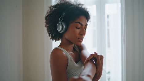 Focused-lady-warming-up-hands-at-home-portrait.-Curly-fit-girl-stretching-arms