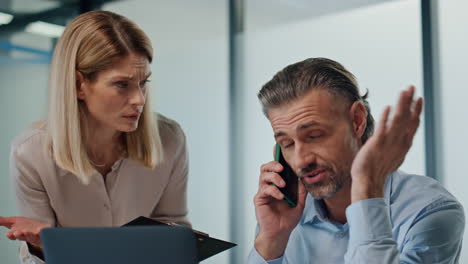 Nervous-businessman-talking-smartphone-office-closeup.-Couple-working-together