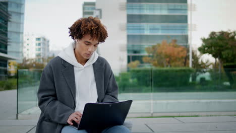 Young-man-working-computer-outdoor-close-up.-Hipster-guy-using-laptop-at-street