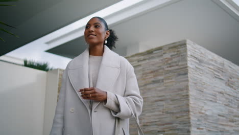 Closeup-smiling-black-hair-woman-posing-at-modern-house.-Stylish-girl-wait-taxi