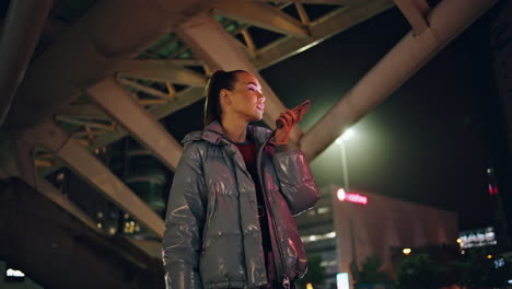 Girl-teenager-recording-voice-message-on-smartphone-standing-night-city-street.