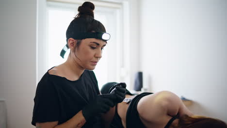 Focused-tattooist-holding-machine-at-home-closeup.-Woman-changing-consumable