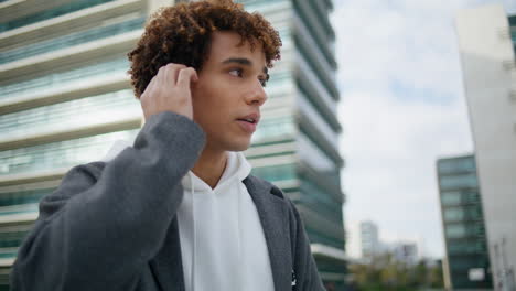 Serious-youngster-calling-earphones-at-urban-settings.-Young-man-making-call