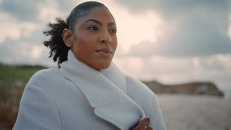 Closeup-pensive-african-american-rest-cloudy-shore.-Black-hair-tourist-get-cold