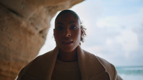 Travel-girl-posing-ocean-cave-closeup.-Smiling-african-american-explore-seashore