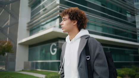 Calm-hipster-walking-downtown-closeup.-Young-man-moving-street-looking-distance